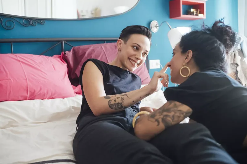Couple lying on a bed and smiling after talking about HPV 
