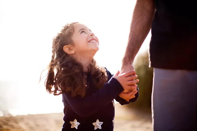 young smiling girl holding a man's hand