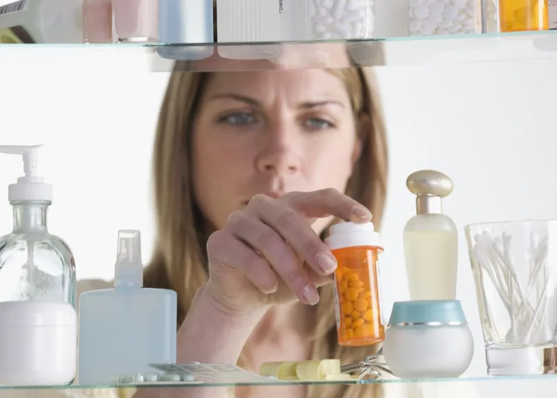 Woman taking pill bottle out of medicine cabinet