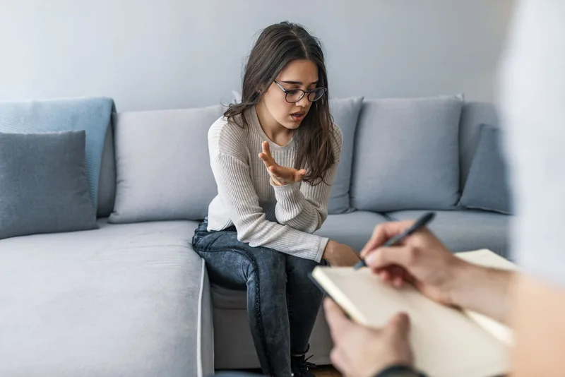 Photo of a therapist writing down notes during therapy with her female patient