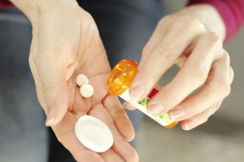 two Adderall pills being transferred from a prescription bottle to a woman's palm