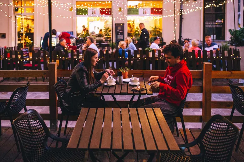 white man and white woman having coffee on a patio