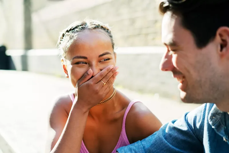 Woman in pink dress laughing at something male companion says