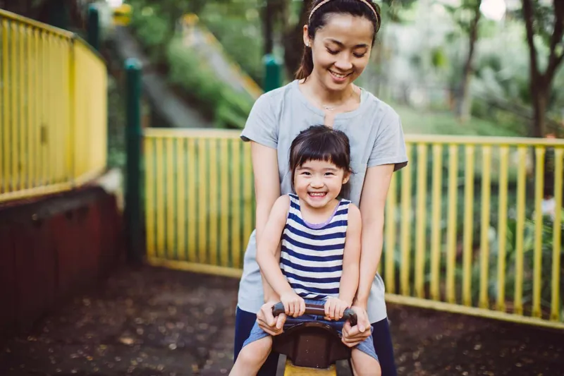 Happy toddler girl with mother at a playground