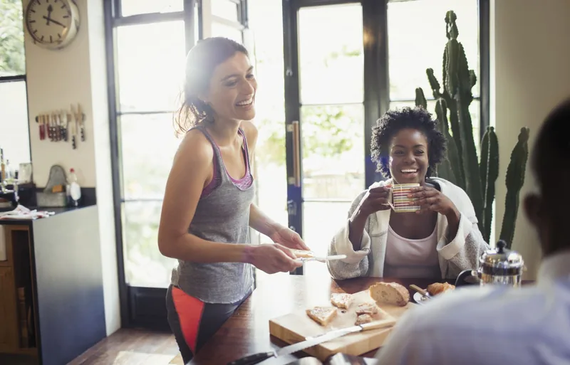 two smiling women enjoying breakfast at kitchen table