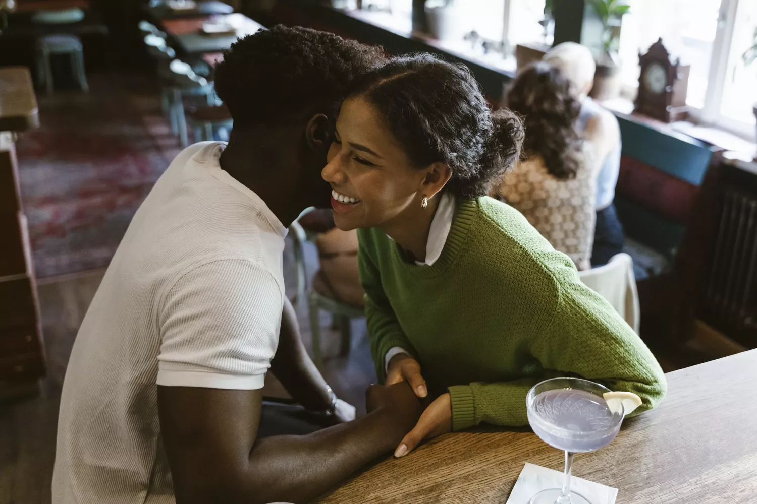 High angle view of man whispering to girlfriend at bar counter in restaurant 