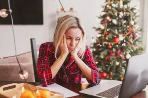 A person looking stressed with Christmas tree in background