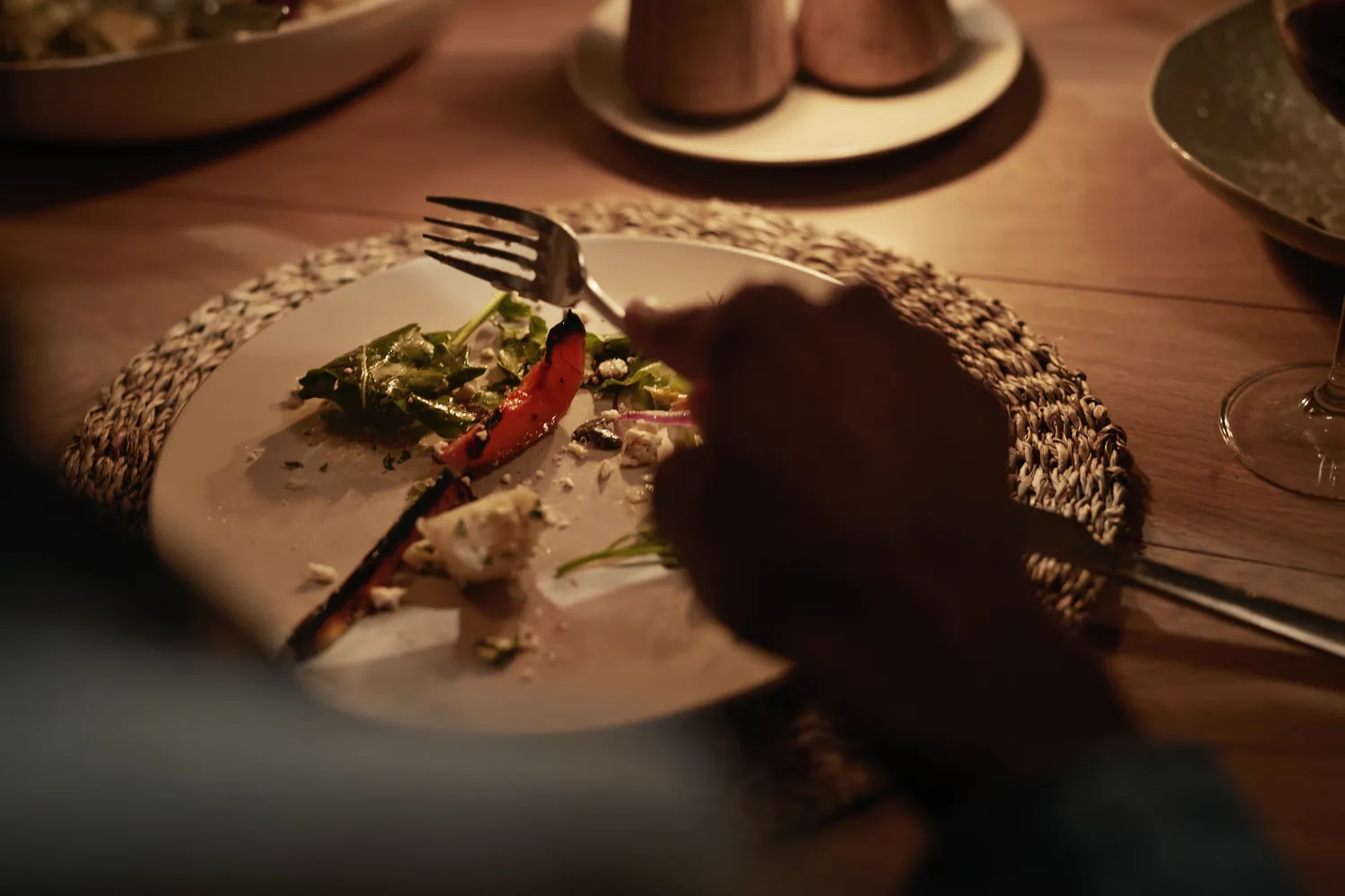 A person dining with a fork and knife some food remains on the plate