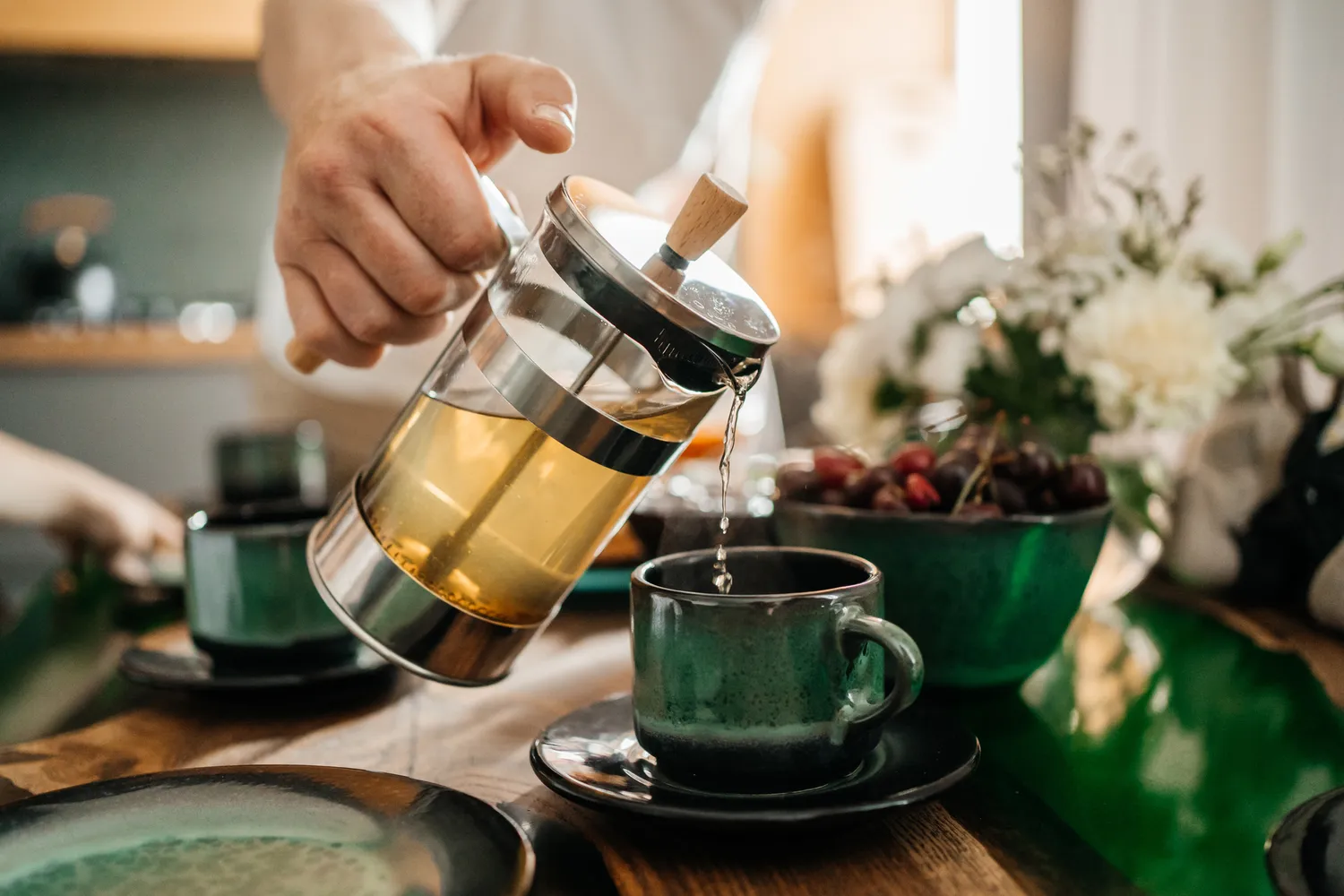 man pouring tea into a green teacup