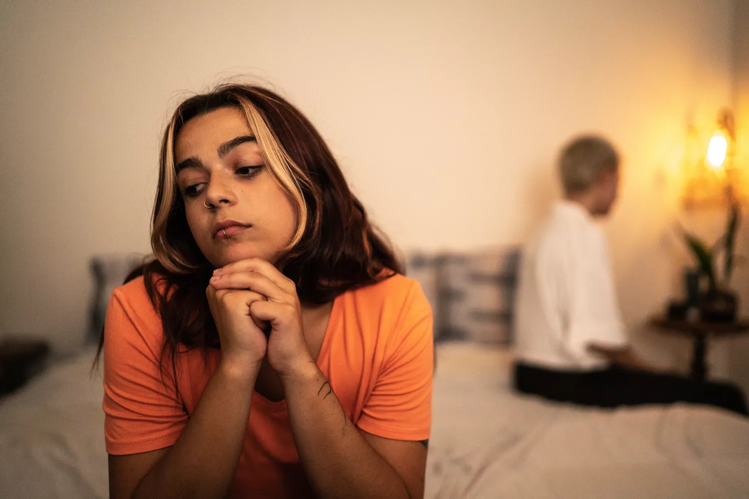 Young lesbian sulking after arguing with her girlfriend in the bedroom at home