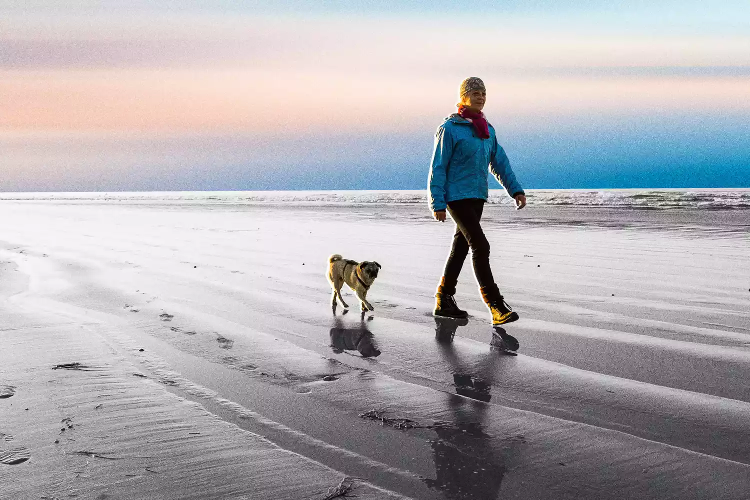 Woman walking on the beach with dog