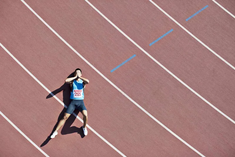 Runner laying on track covering his face
