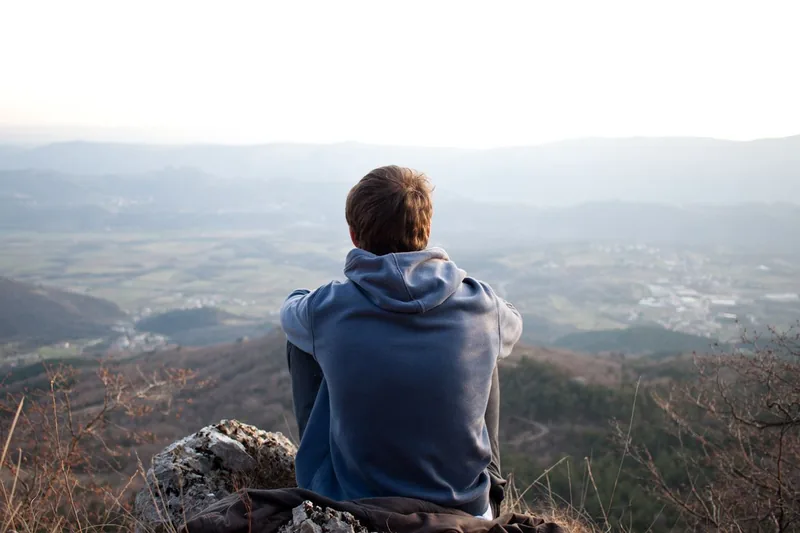 Man sitting on a hill looking out