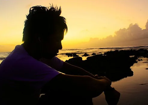 A person standing defiantly against a dark, cloudy sky, symbolizing resilience against negativity.