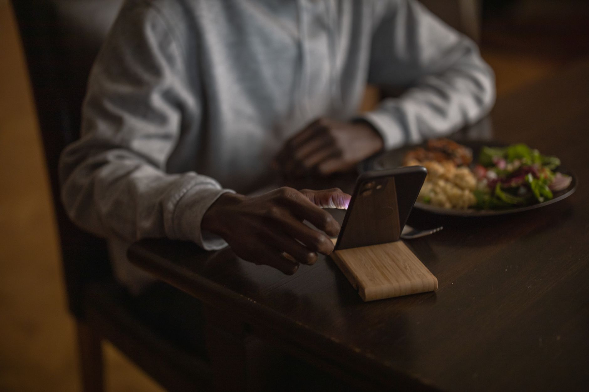 An individual engages with a smartphone while dining, showcasing modern lifestyle habits.