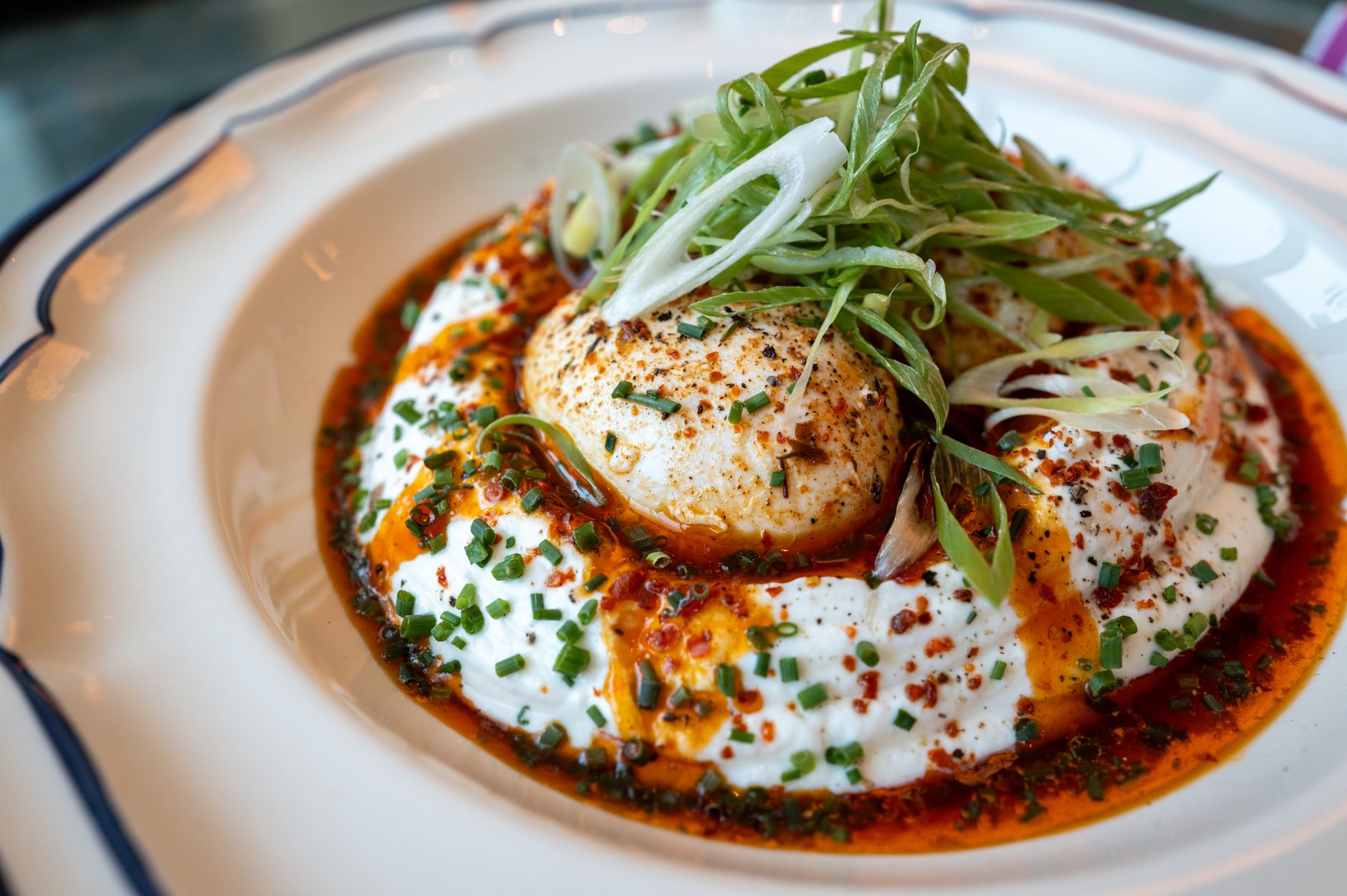 Close-up of poached eggs with spiced yogurt, garnished with herbs.