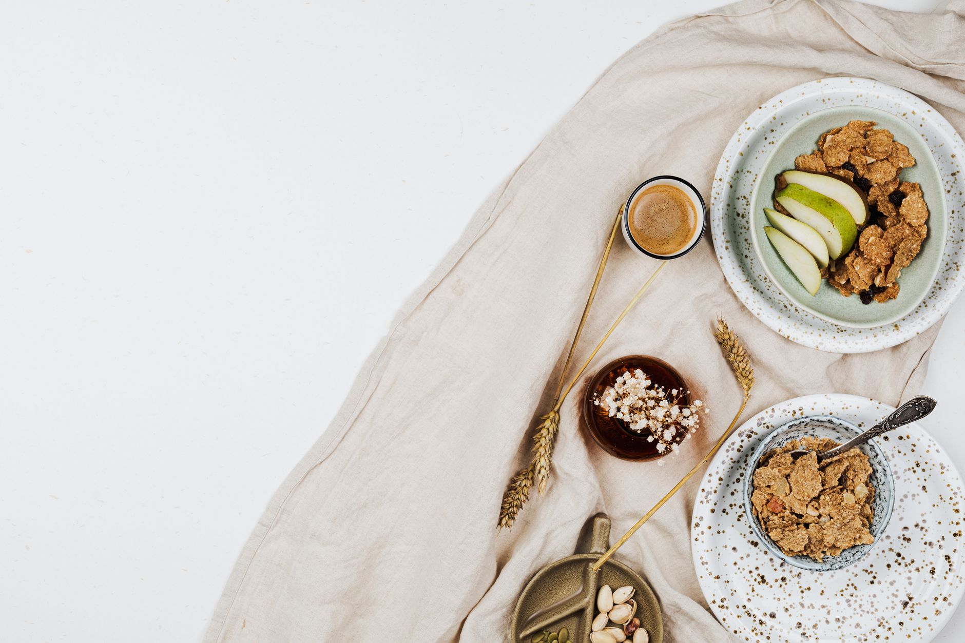 A flat lay of a nutritious breakfast featuring cereal bowls with fresh fruits, espresso, and nuts.