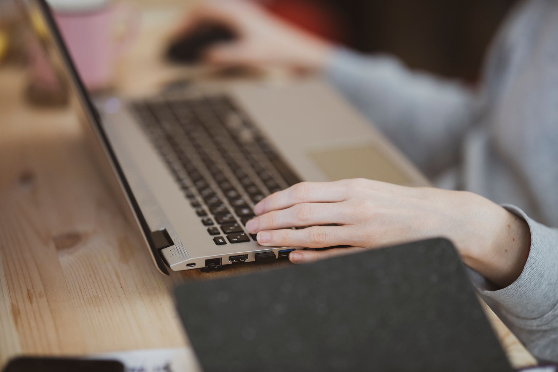 Close-up view of a person typing on a laptop with focus on the hand and keyboard.