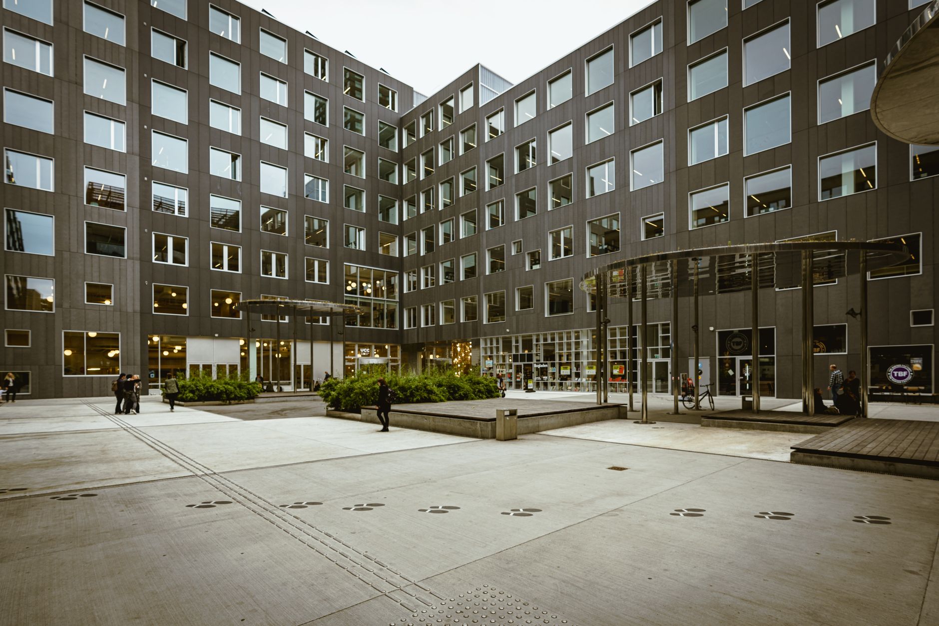 A spacious urban courtyard surrounded by modern office buildings with people walking.