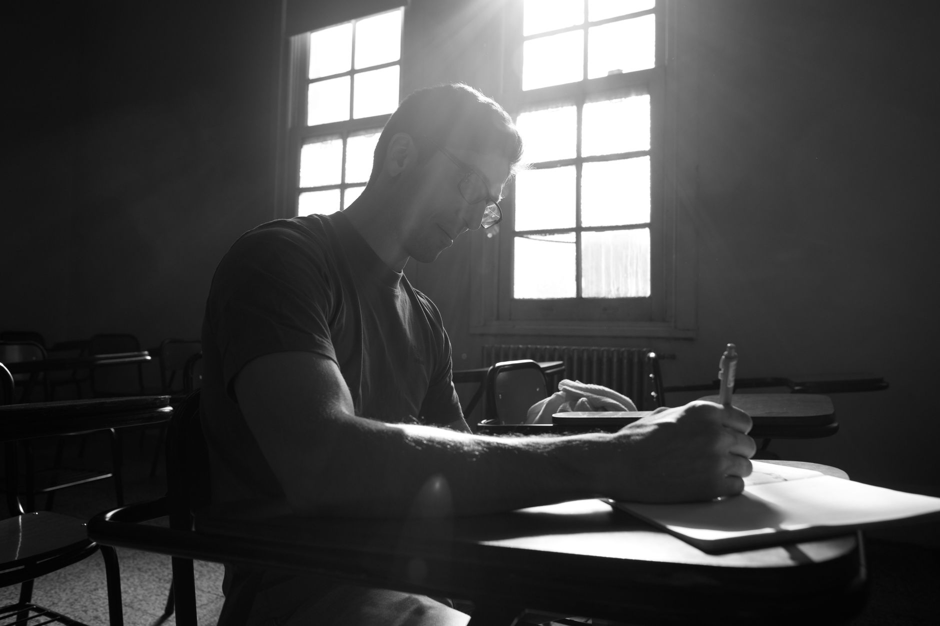 Black and white image of a student studying by a window in a classroom, Buenos Aires.