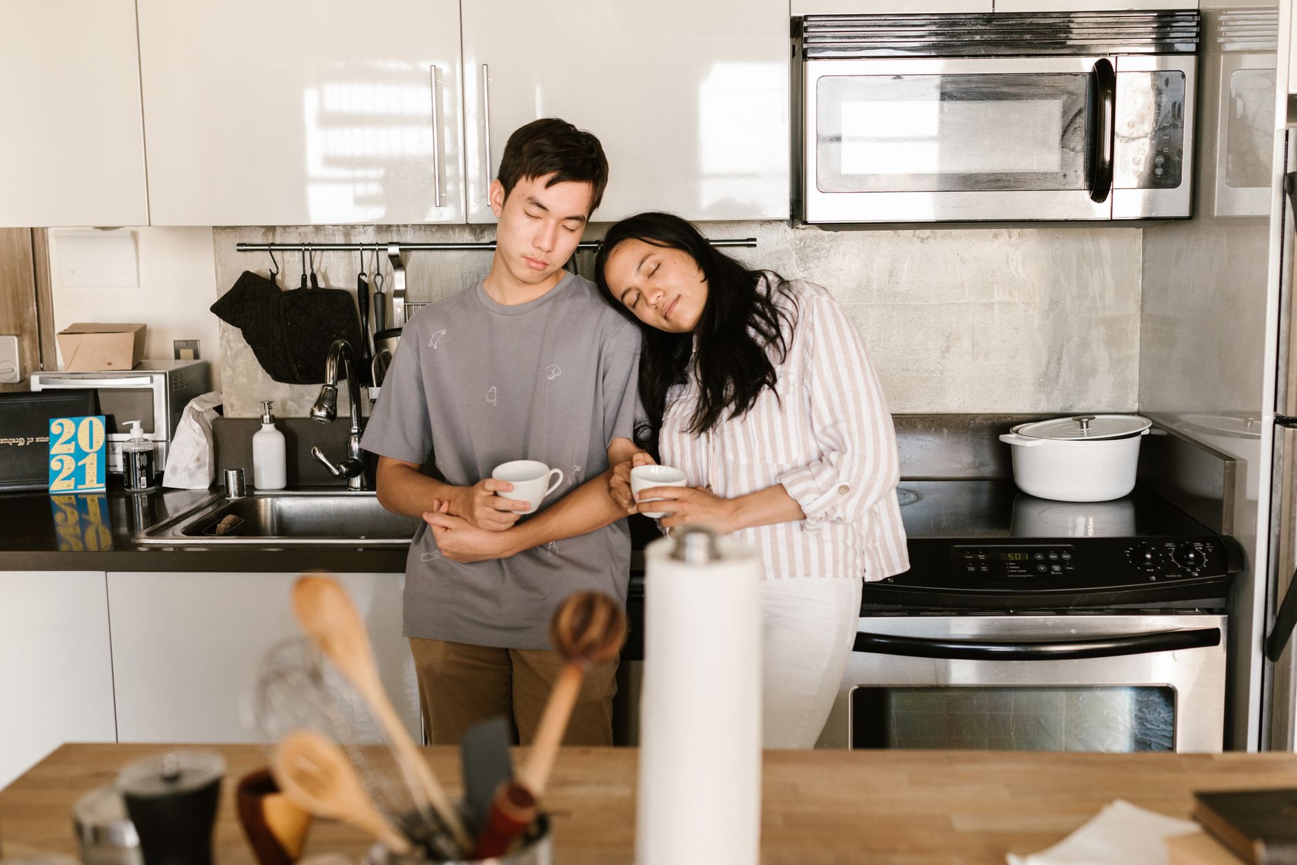 Two adults enjoying a quiet morning in the kitchen with cups in hand, radiating serenity.