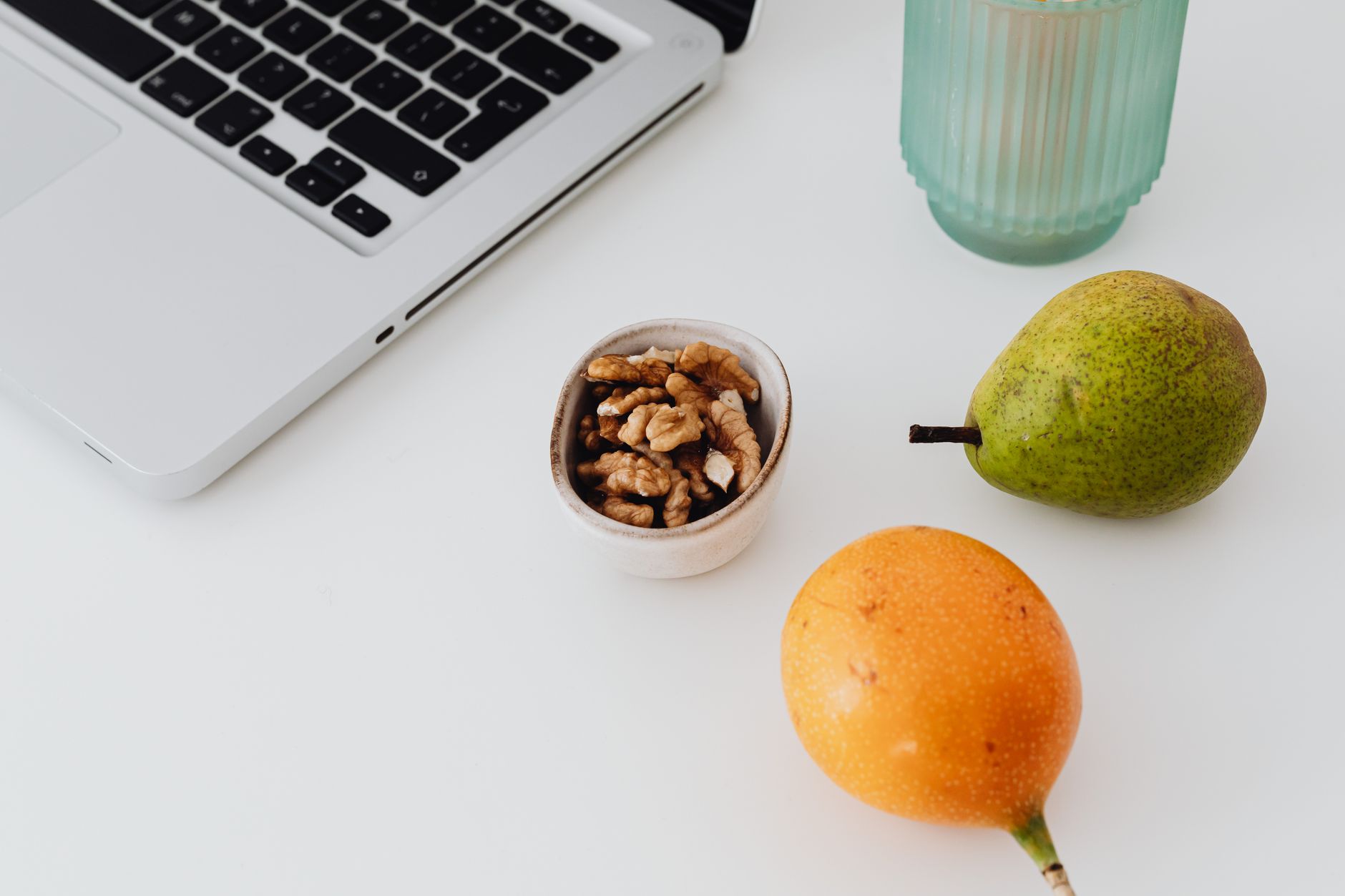 A desk setup featuring a laptop, fruits, and snacks for a productive and healthy work environment.